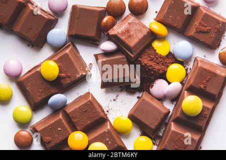 once di cioccolato e di tartarughe mescolate su uno sfondo bianco di cacao in polvere Foto Stock