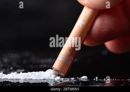Linea di cocaina che è russata da un uomo con una fattura arrotolata. Primo piano, scatto macro Foto Stock