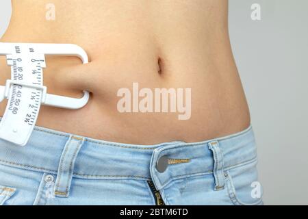 Calibri grassi del corpo, donna che misura la percentuale sottocutanea di grasso sulla pancia. Giovane donna che usa calibri a pieghe. Foto Stock