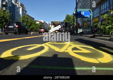 Berlino, Germania. 27 maggio 2020. Un simbolo di bicicletta appena spruzzato può essere visto su un percorso ciclabile temporaneo appena creato su Frankfurter Allee. Sullo sfondo è una bicicletta con un banner con l'iscrizione 'più spazio per la bicicletta'. Credit: Sven Braun/dpa-Zentralbild/ZB/dpa/Alamy Live News Foto Stock