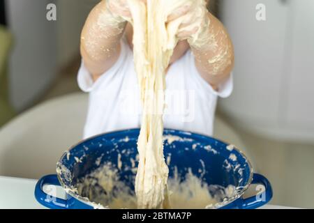 3-4 anni ragazza impasta lievito impasto in una padella blu, mani closeup. tempo libero per la famiglia Foto Stock