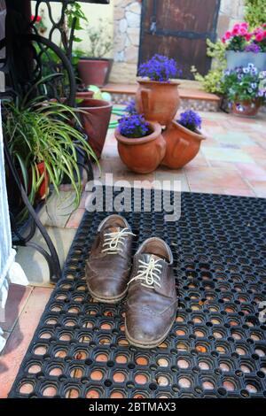 Scarpe da uomo sul tappeto di fronte alla porta Foto Stock