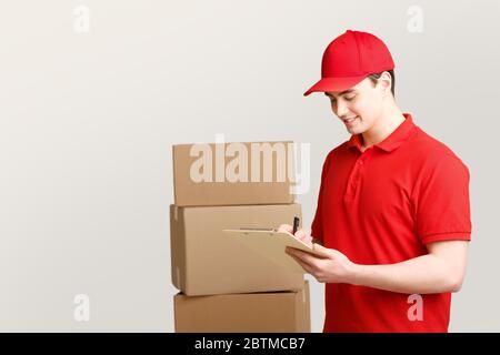 Corriere in magazzino con scatole prende appunti su sfondo chiaro Foto Stock