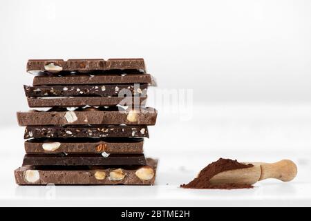 Diversi tipi di cioccolatini con frutta a guscio cacao in polvere e menta - fuoco selettivo, fondo bianco Foto Stock