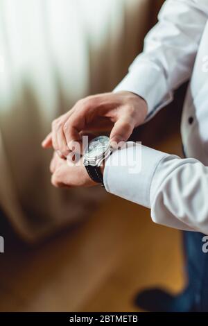 uomo d'affari che controlla l'ora sul suo orologio da polso, uomo che mette l'orologio a portata di mano, sposo che si prepara al mattino Foto Stock