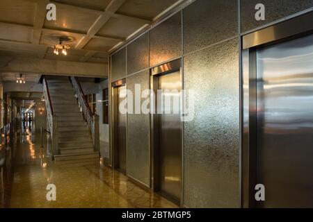 La sala poco illuminata del Monadnock Building con tre ascensori presso una delle sue splendide scale in alluminio, Chicago, Illinois, USA Foto Stock