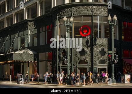 L'ingresso nord-ovest del Sullivan Center, con il suo lavoro ornamentale in ghisa illuminato dal sole e le persone che aspettano di attraversare la strada, Chicago, Illinois Foto Stock