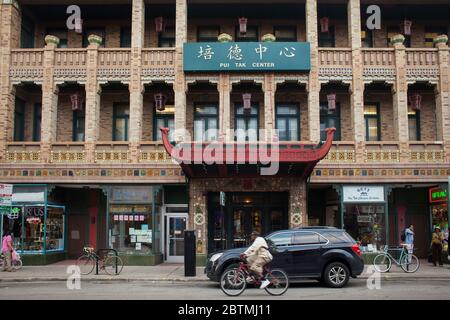 Vista orizzontale di un ciclista e di un'auto passando per lo storico centro della comunità cinese Pui Tak, Chinatown, Chicago, Illinois, USA Foto Stock