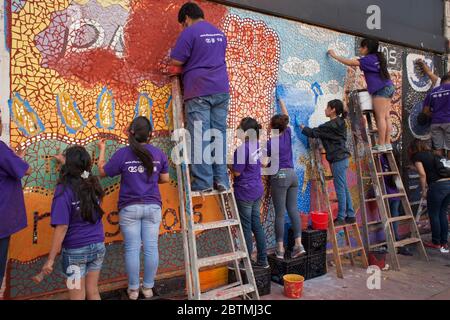 Gruppo di studenti, supervisionati dal loro insegnante, che fanno un mosaico colorato su una parete del Pilsen Historic District, Lower West Side, Chicago, Illinois Foto Stock