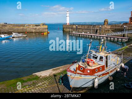 Newhaven, Edimburgo, Scozia, Regno Unito, 27 maggio 2020. UK Meteo: Barche da pesca ormeggiate nelle acque calme del porto creano riflessi con una barca sul lato del porto che pulisce il suo scafo Foto Stock