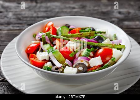 Verdure biologiche classiche insalata greca con asparagi alla griglia, pomodori ciliegini, cetrioli, olive nere, anelli di cipolla rossa con olio d'oliva, formaggio feta s. Foto Stock