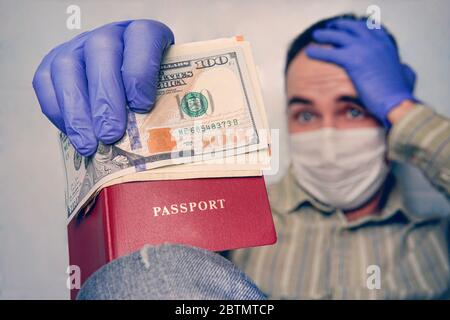 vacanza annullata a causa della pandemia del covid-19. turista annoiato è messo in quarantena a casa, indossando una maschera e guanti, guardando il suo passaporto e denaro Foto Stock