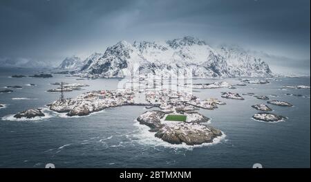 Un campo da gioco di calcio incredibile, situato a Henningsvaer, Lofoten, Norvegia. Campo da calcio verde su un'isola rocciosa. Montagne lontane coperte di neve. Antenna Foto Stock