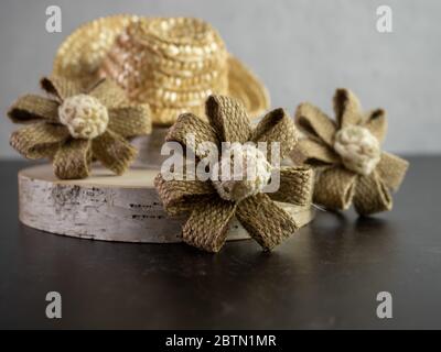 3 fiori di tela e un cappello di paglia seduto su vero legno per un arredamento rustico casa di campagna. Foto Stock