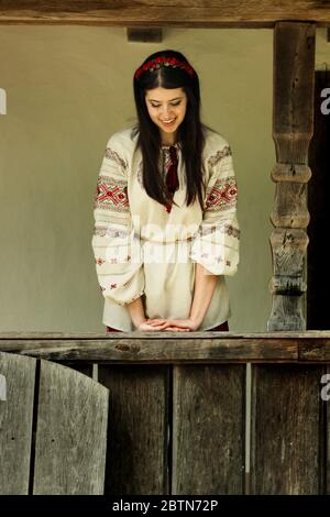 bella donna brunette in nazionale ucraino ricamo vestiti sullo sfondo di vecchia casa di legno nativo Foto Stock