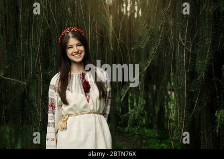 bella donna felice in nazionale ucraino ricamo vestiti sorridente sullo sfondo di albero Foto Stock