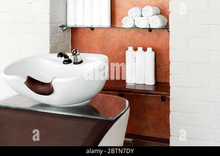 Ciotola per capelli nel salone di bellezza interno. Lavello per lavare i capelli, trattamenti di cura dei capelli in barbiere, shampoo, asciugamani. Parrucchiere stilista Foto Stock