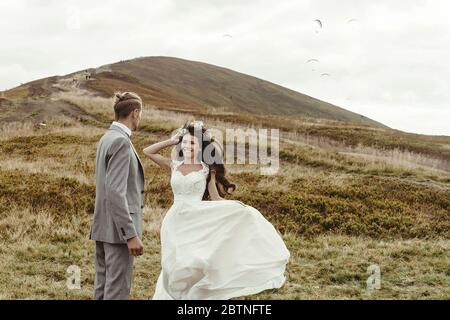 felice splendida sposa correre per sposare e divertirsi, cerimonia di lusso in montagna con vista incredibile, spazio per il testo, boho matrimonio coppia Foto Stock