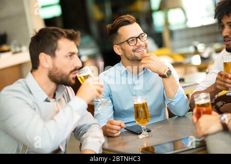 conversazione di giovani uomini d'affari mentre si siedono in un bar e bevono birra di grano freddo Foto Stock