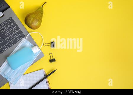 maschera protettiva, gel disinfettante e forniture per ufficio su sfondo giallo, concetto di nuova normalità sul lavoro e protezione contro i virus, copy sp Foto Stock