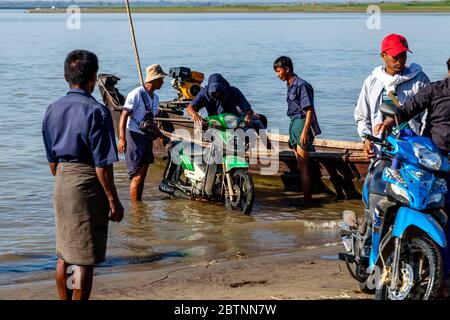 Merci e Moto che vengono scaricati da UNA barca sul fiume Irrawaddy, (Ayeyarwady), Bagan, Regione Mandalay, Myanmar. Foto Stock