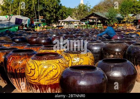 Un uomo birmano guardando grandi contenitori di ceramica in vendita fuori Ananda Tempio, Bagan, Mandalay Regione, Myanmar. Foto Stock