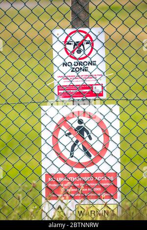 Primo piano del cartello di avvertimento pubblico del Ministero della Difesa 'No Drone zone' dietro la rete di collegamento della catena di barriera di sicurezza recinzione, RAF Fairford, Regno Unito. Nessun segno di accesso. Foto Stock