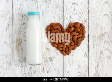 Latte vegano da mandorle noci su rustico tavolo di legno Foto Stock