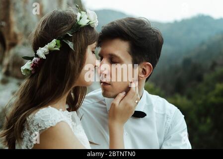 felice coppia di sposi di lusso abbracciando con gara sulla cima di una montagna in serata Foto Stock