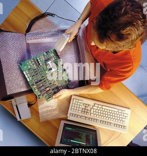 Vista dall'alto di un addetto al magazzino che codifica i componenti del computer da spedire con un lettore di barre. Foto del 1990 Foto Stock