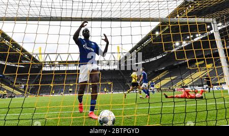 Salif Sane di Schalke reagisce in gol dopo che Raphael Guerreiro di Dortmund ha segnato il secondo gol del suo fianco contro il portiere di Schalke Markus Schubert, a destra, durante la partita di calcio tedesca della Bundesliga tra Borussia Dortmund e Schalke 04 a Dortmund, Germania, sabato 16 maggio 2020. La Bundesliga tedesca diventa la prima importante lega di calcio al mondo a riprendere dopo due mesi di sospensione a causa della pandemia del coronavirus. Foto Stock