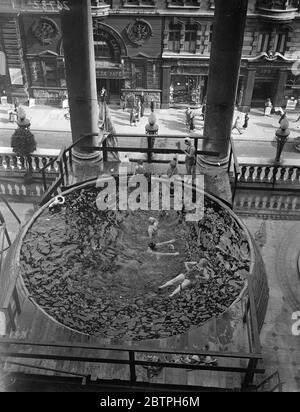 Bagni sopra il traffico Piccadilly . Una piscina è stata collocata sul balcone terrazzato dell'hotel Piccadilly e i bagnanti si tuffano nell'acqua appena sopra il traffico stradale. Bagnanti nella piscina sopra la strada. 3 agosto 1932 Foto Stock