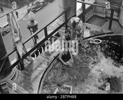 Bagni sopra il traffico Piccadilly . Una piscina è stata collocata sul balcone terrazzato dell'hotel Piccadilly e i bagnanti si tuffano nell'acqua appena sopra il traffico stradale. Bagnanti nella piscina sopra la strada. 3 agosto 1932 Foto Stock