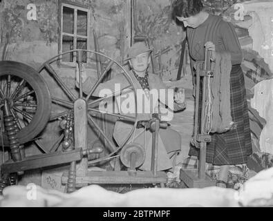 Ann Harding prova la ruota di filatura alla mostra tessile scozzese a Londra . La Miss Ann Harding , l'attrice del film , ha aperto la mostra di textil scozzese alla British Industries House , Oxford Street . Una delle caratteristiche del display è la tessitura del tartan di William Meikle per soddisfare la domanda di coronazione . Si stima che almeno £ 2 , 000 di chilts saranno indossati alla cerimonia dell'Abbazia di Westminster . Foto , Miss Ann Harding prova la sua mano alla ruota che gira assistita dalla signora William Meikle . 12 marzo 1937 Foto Stock