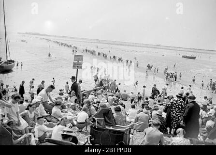 Alla ricerca di gocce di mare!. Con la temperatura in aumento negli anni '80, la marea ha scelto questa settimana per essere fuori per la maggior parte della giornata a Southend, Essex. Di conseguenza, migliaia di visitatori del Southend possono essere visti vagare sul fango alla ricerca di pudddles in cui mantenere fresco. 4 agosto 1938 Foto Stock