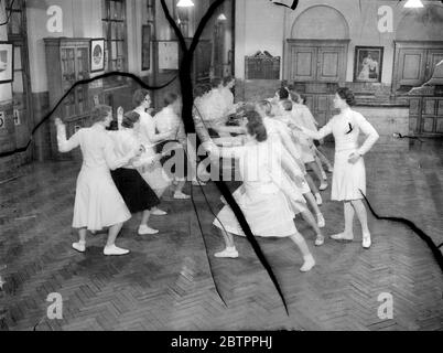 East End ragazze 'en Garde!'. Le ragazze lavoranti dell'East End di Londra stanno imparando a recinarsi al Faircough Institute del London County Council di Berner Street, Commercial Road. Sotto la direzione di Miss Eleanor MacDonald, il giovane esperto di scherma che sta agendo come istruttore, lo sport sta guadagnando popolarità nel East End, dove le ragazze riconoscono il suo valore come un aiuto alla forma fisica e alla grazia di figura. Spettacoli fotografici, una classe di mencatrici di bambine sotto l'istruzione di Miss Eleanor MacDonald, al Faircough Institute. 1 febbraio 1938 Foto Stock