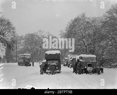 Distruzione della neve nel sud dell'Inghilterra. Traffico trattenuto. Il peggior caos della grande tempesta di neve che ha imperversato sull'Inghilterra meridionale è stato causato nel distretto di Lyndhurst della New Forest, dove i cavi telefonici sono stati abbattuti mentre gli alberi caddero, tagliando le comunicazioni in tutte le direzioni. Le strade principali sono state bloccate e il quartiere è caduto nel buio dalla rottura dei cavi di alimentazione. Spettacoli fotografici, traffico in direzione della neve sulla Lyndhurst Road. 8 dicembre 1937 Foto Stock