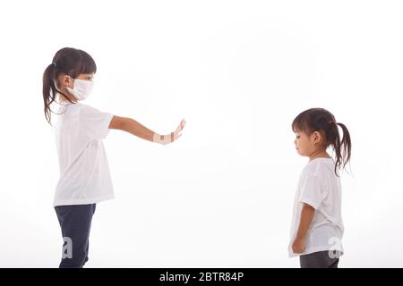 Concetto di distanza sociale. Due bambini asiatici che indossano maschera in piedi a 2 metri di distanza da altre persone mantenere la distanza di protezione da COVID-19 e il rischio o Foto Stock