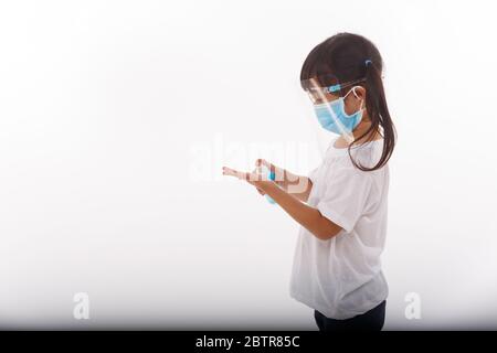 Cute ragazza asiatica che indossa una maschera e le lavano le mani con alcool per evitare di diffondere la malattia su uno sfondo bianco. Prevenzione della diffusione di Foto Stock