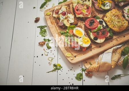 Gustosi panini fatti in casa con vari ingredienti serviti su tritare in legno Foto Stock