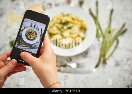 Donna che fa una foto con uno smarthone di tagliatelle fatte in casa con ricotta cremosa Foto Stock