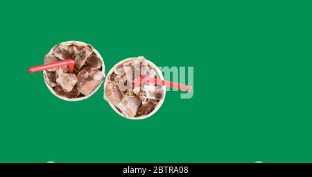 Due bicchieri con una bevanda e ghiaccio su sfondo verde, con tubi rossi per il succo. Foto Stock