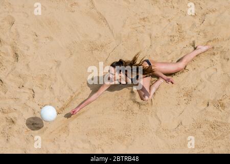 Vista superiore del giocatore di Pallavolo femminile in spiaggia al servizio Foto Stock