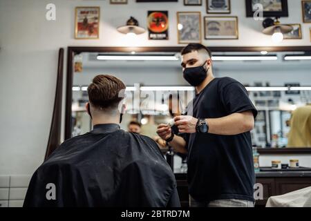 Barber fa un taglio di capelli e acconciatura in un barbiere, salone di bellezza. Foto Stock