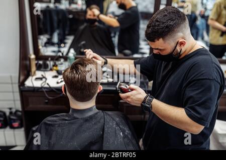 Barber fa un taglio di capelli e acconciatura in un barbiere, salone di bellezza. Foto Stock