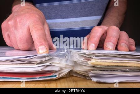 Chiudere la foto POV delle mani di un uomo con una pila di documenti/documenti aziendali e indicando una particolare area di interesse. Foto Stock