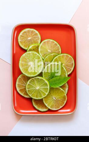 Fette di lime con foglie verdi su dich su sfondo di carta a due colori Foto Stock