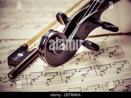 Dettaglio del vecchio violino con fiddlestick sulle note musicali in un look vintage Foto Stock