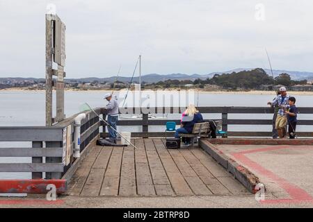 Monterey, California, USA - 09 giugno 2015: Pescatori che pescano su un molo di legno. Baia e montagna sullo sfondo. Foto Stock