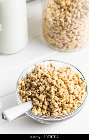 Grano soffiato coperto di miele in una ciotola di vetro. Colazione a base di cereali su un tavolo da cucina. Foto Stock